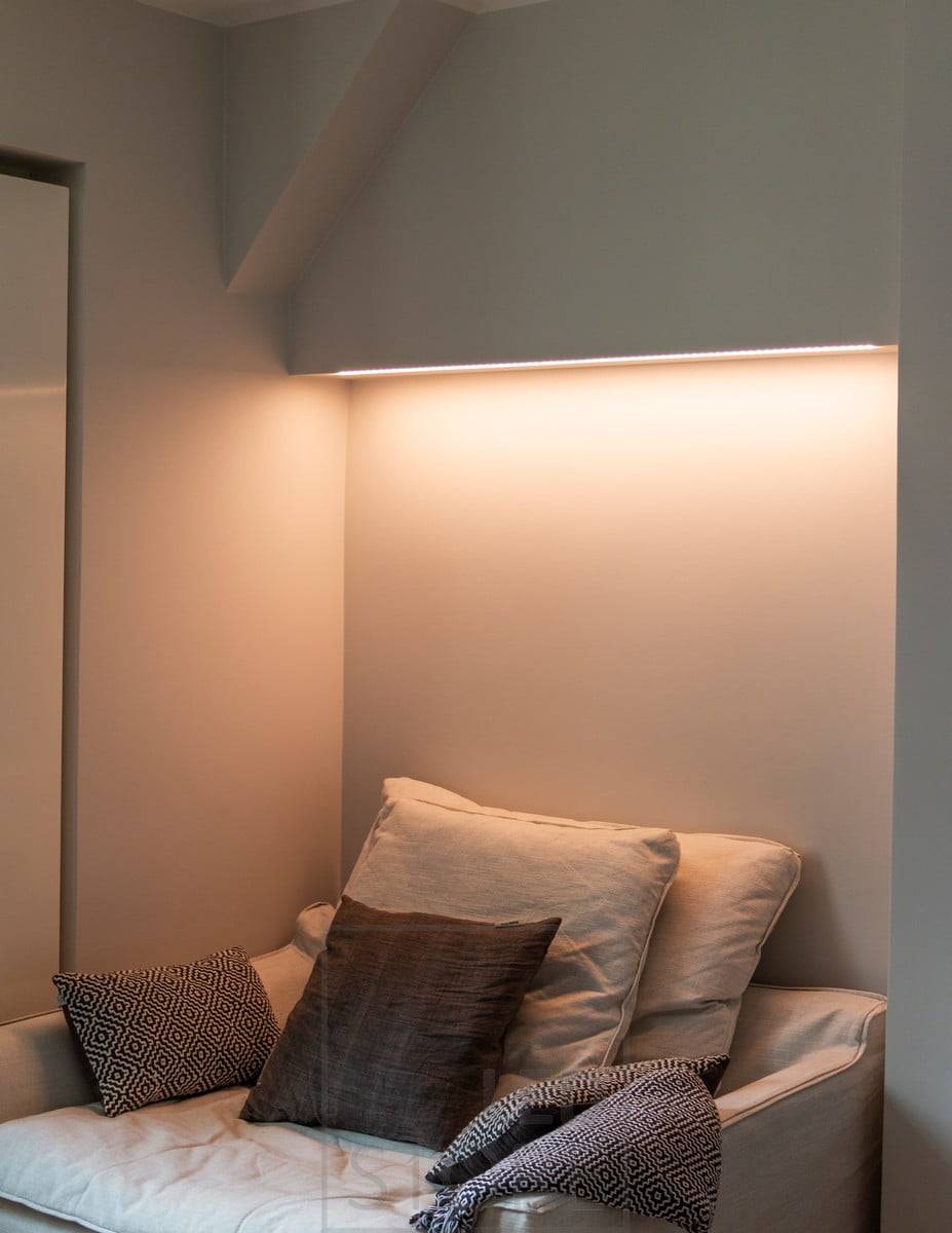 Bonita iluminación ambiental encima de la cama en el dormitorio. La tira de LED regulable en temperatura de color le permite ajustar la luz según su estado de ánimo y sus necesidades.